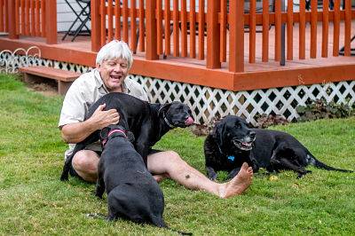 Man on his lawn playing with his dogs