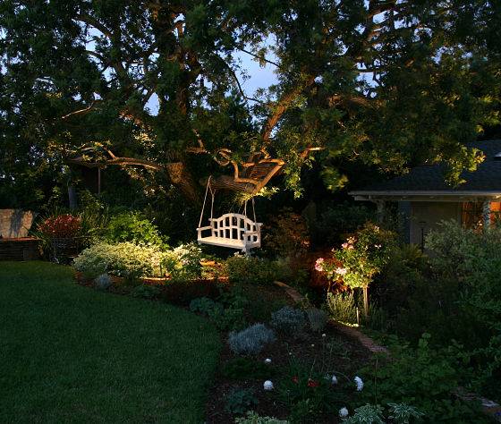 Garden swing with landscape lighting in addition to professional patio lighting.