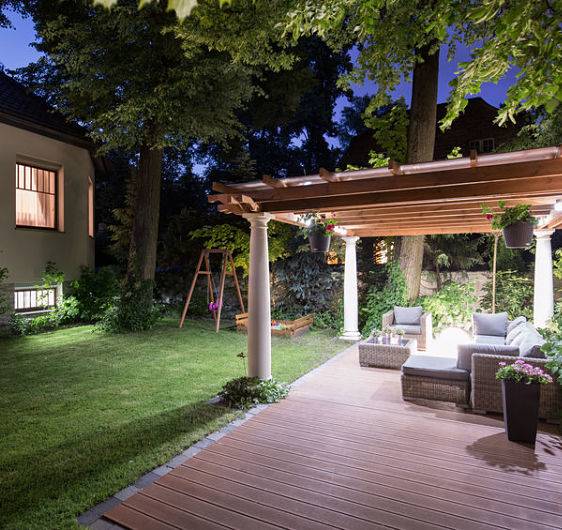 A backyard with a covered patio and a patio lighting system done by American National Sprinkler & Lighting.