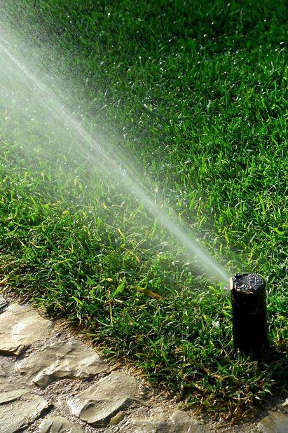 A home irrigation system with a corner sprinkler system by a pathway.