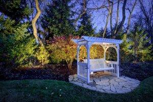 American National Sprinkler & Lighting - automatic lighting system illuminating a white bench in the backyard.